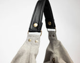 Close-up of a gray bag with black leather handle on a white background