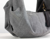 Gray handbag with a black strap on a white background