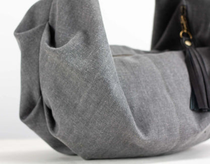 Gray handbag with a black strap on a white background