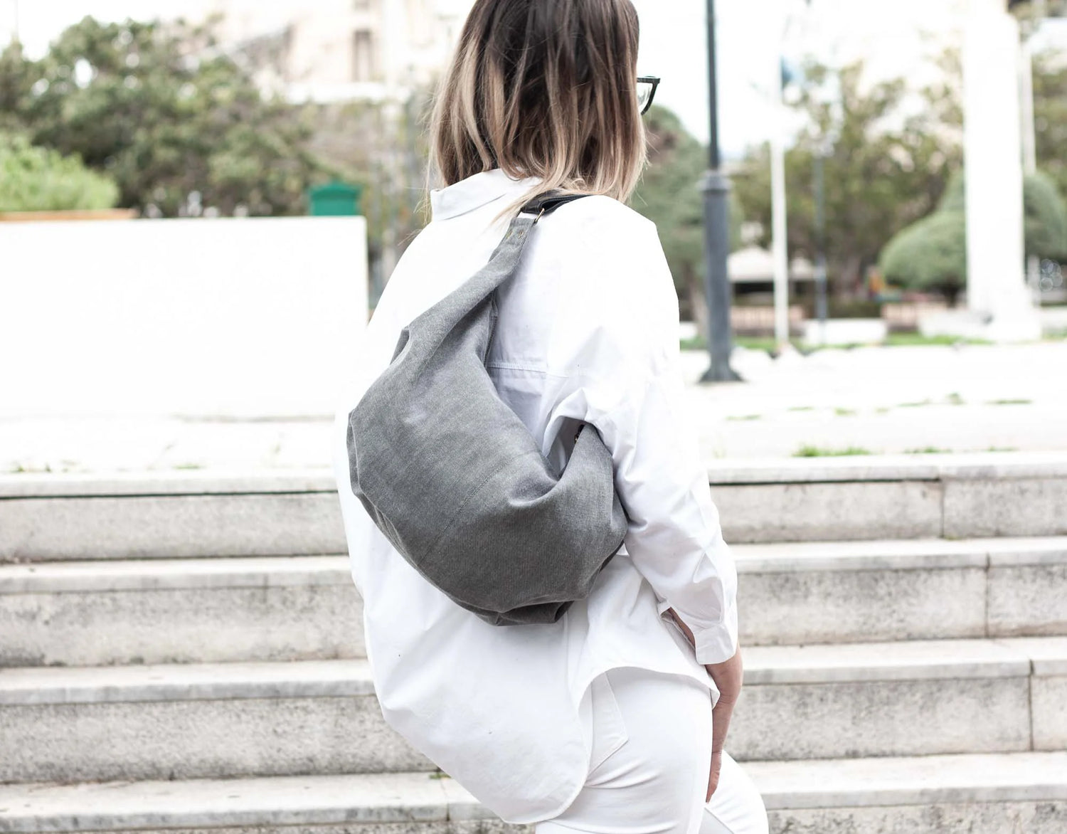Person wearing a gray sling bag on a city street