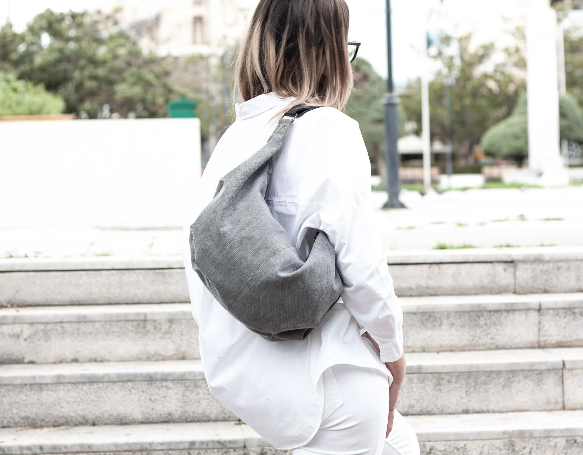 Person wearing a gray sling bag on a city street