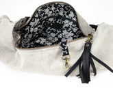 Handbag with floral interior lining and black tassel on a white background