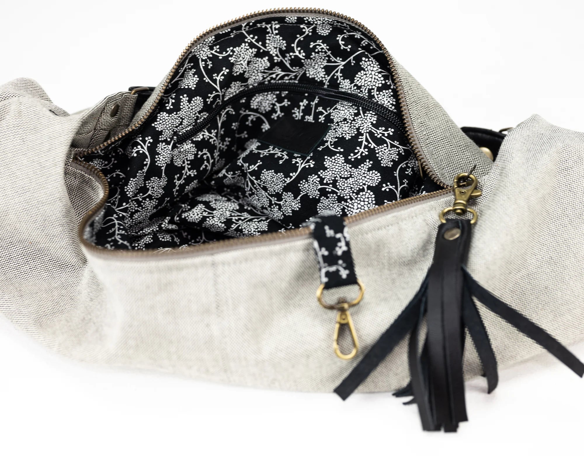 Handbag with floral interior lining and black tassel on a white background