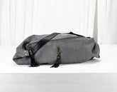 Gray duffel bag with black straps on a white background