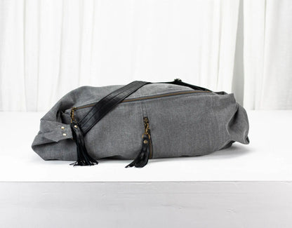 Gray duffel bag with black straps on a white background