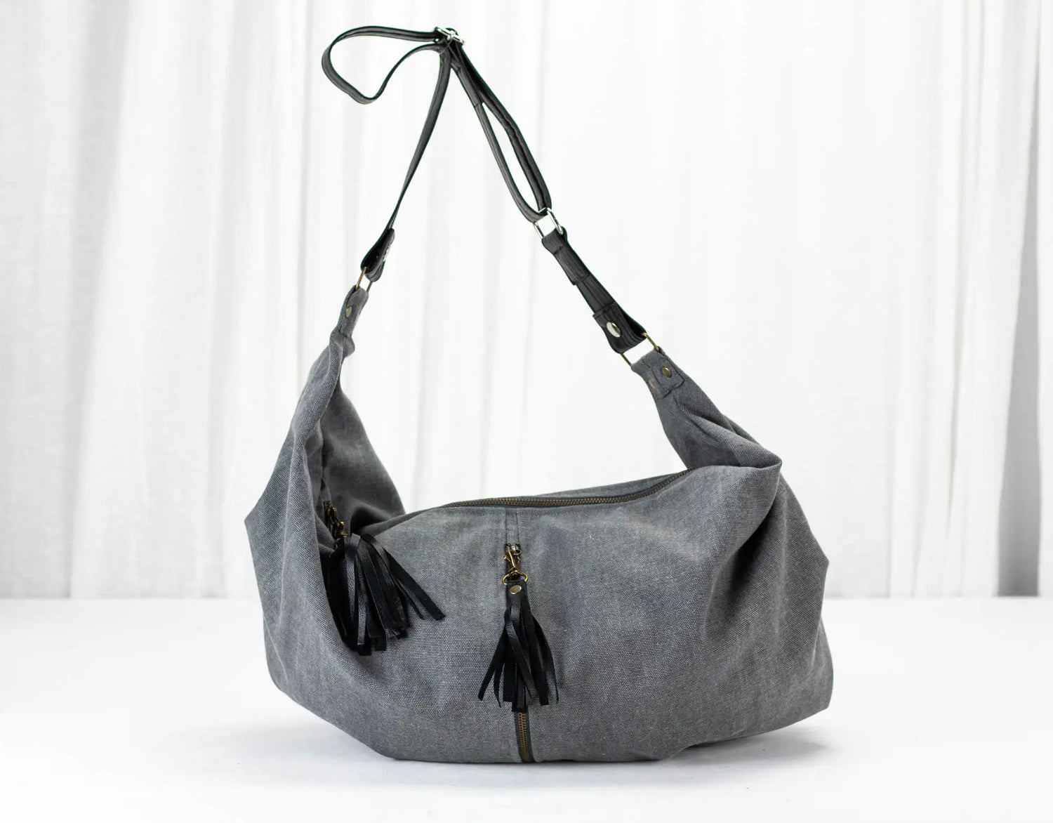 Gray shoulder bag with black tassels on a white background