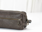 Close-up of a gray leather pouch with a zipper on a white background