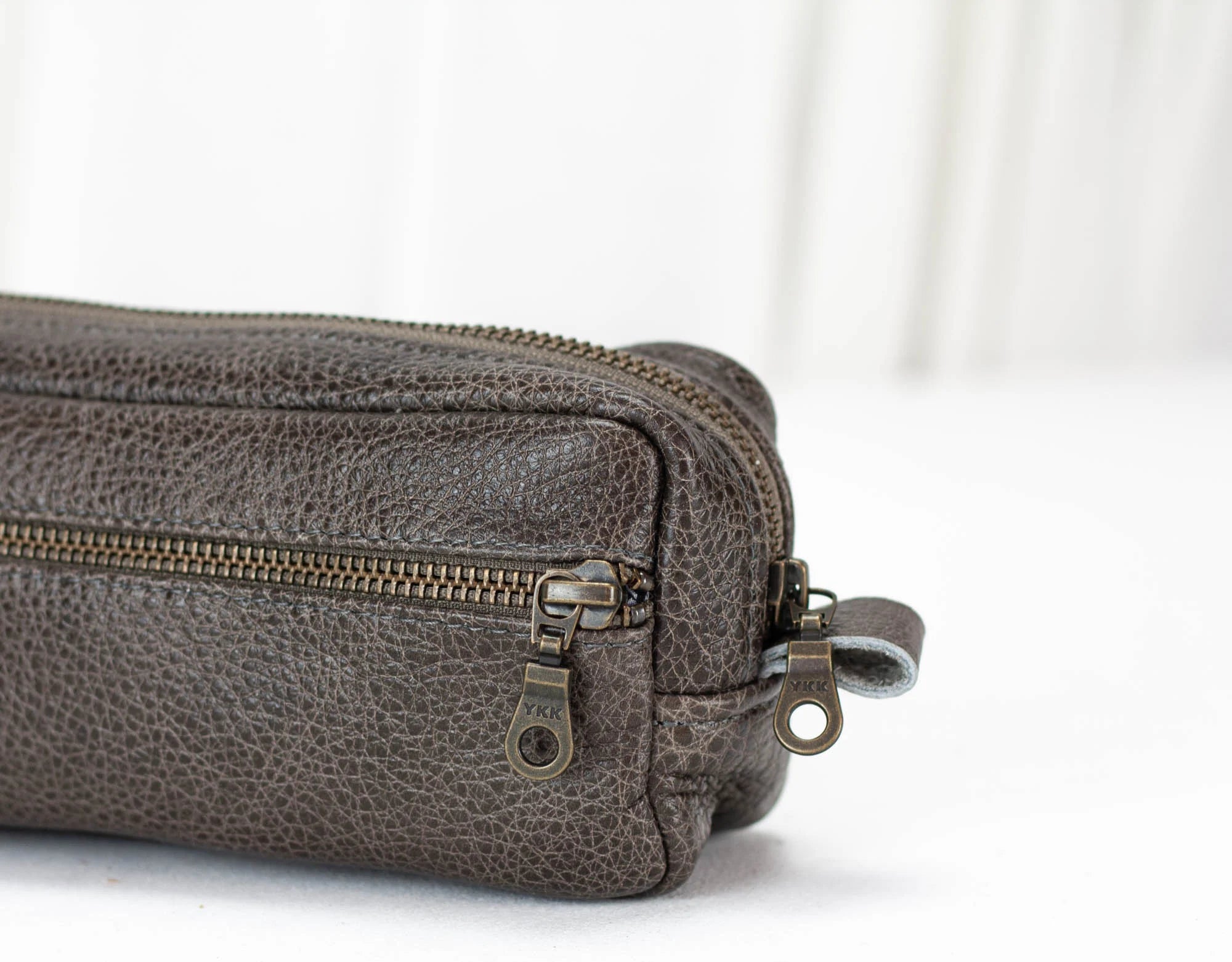 Close-up of a gray leather pouch with a zipper on a white background