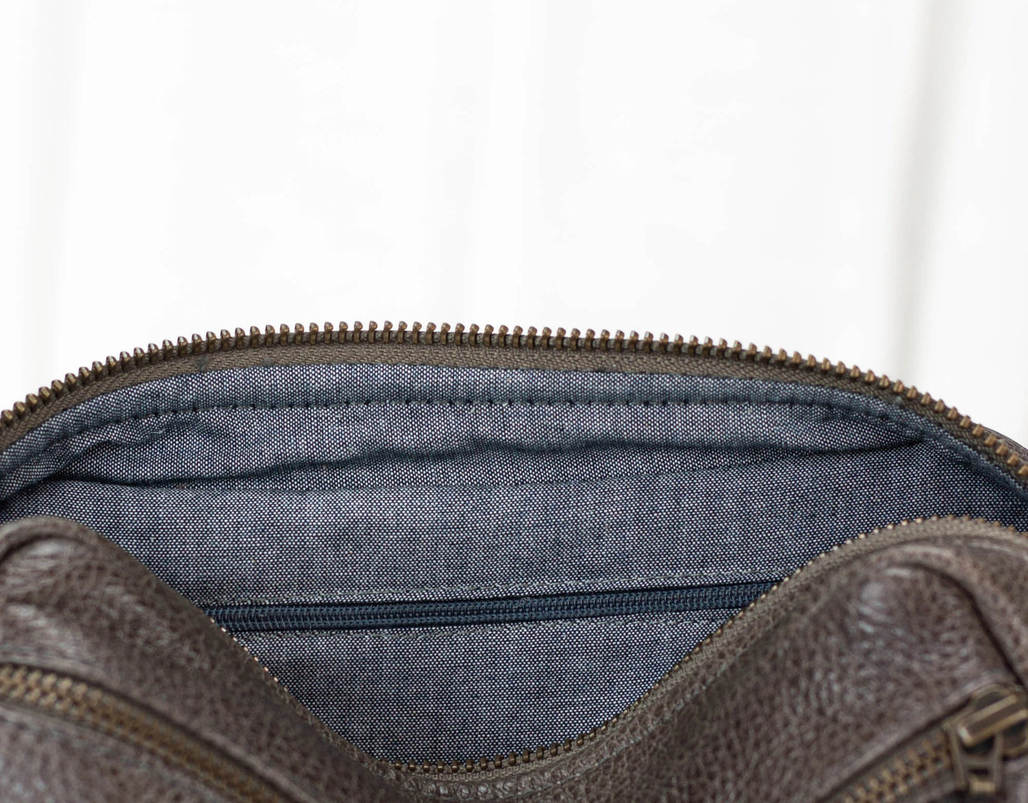 Brown leather bag with blue interior lining on a white background