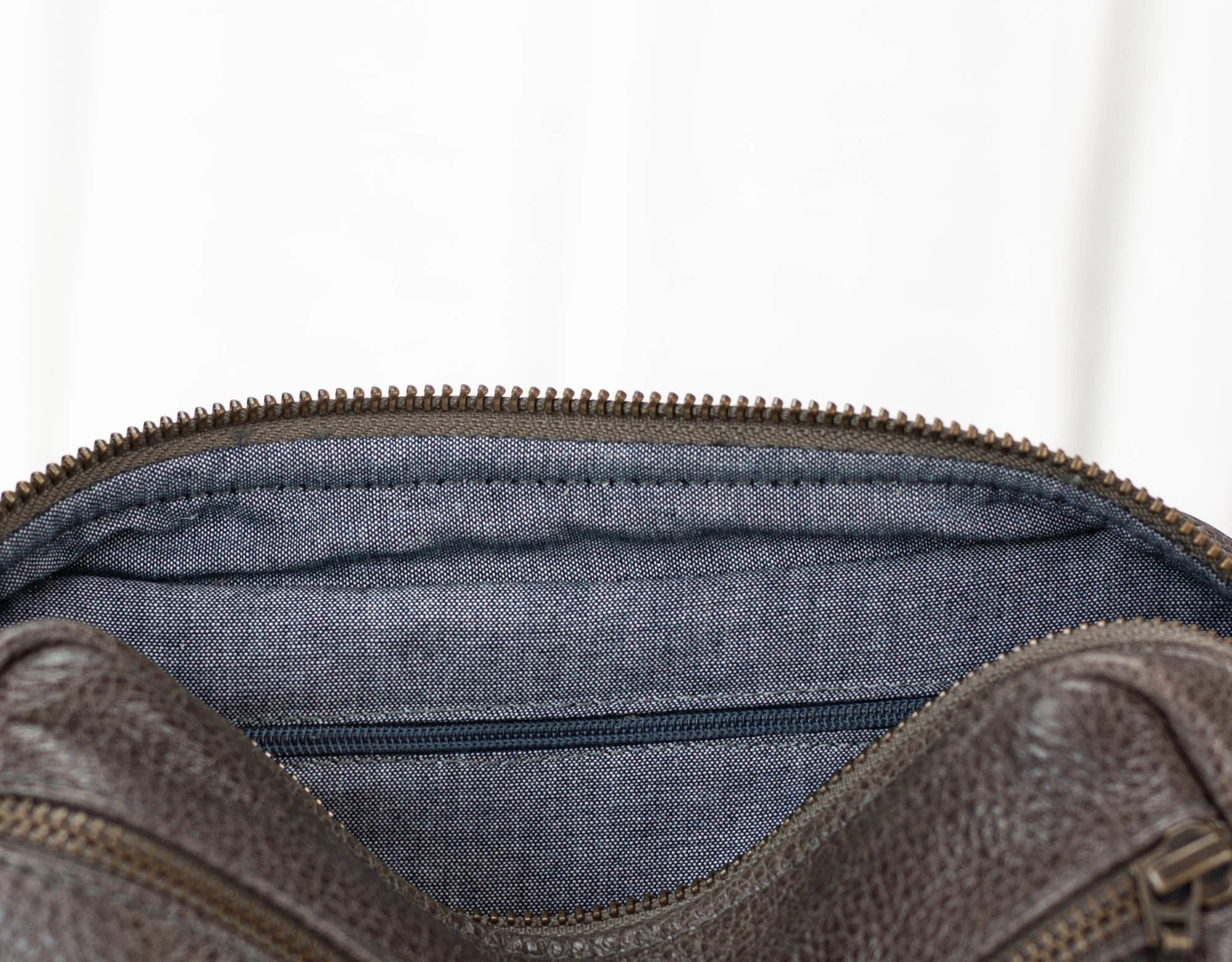 Brown leather bag with blue interior lining on a white background