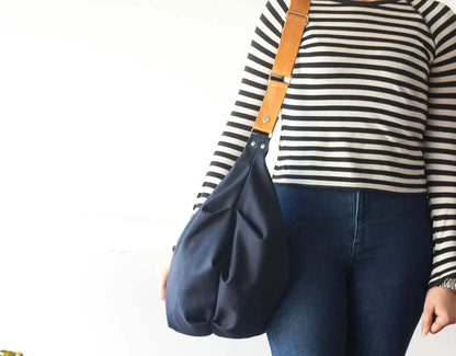 Person holding a navy blue handbag with a white background