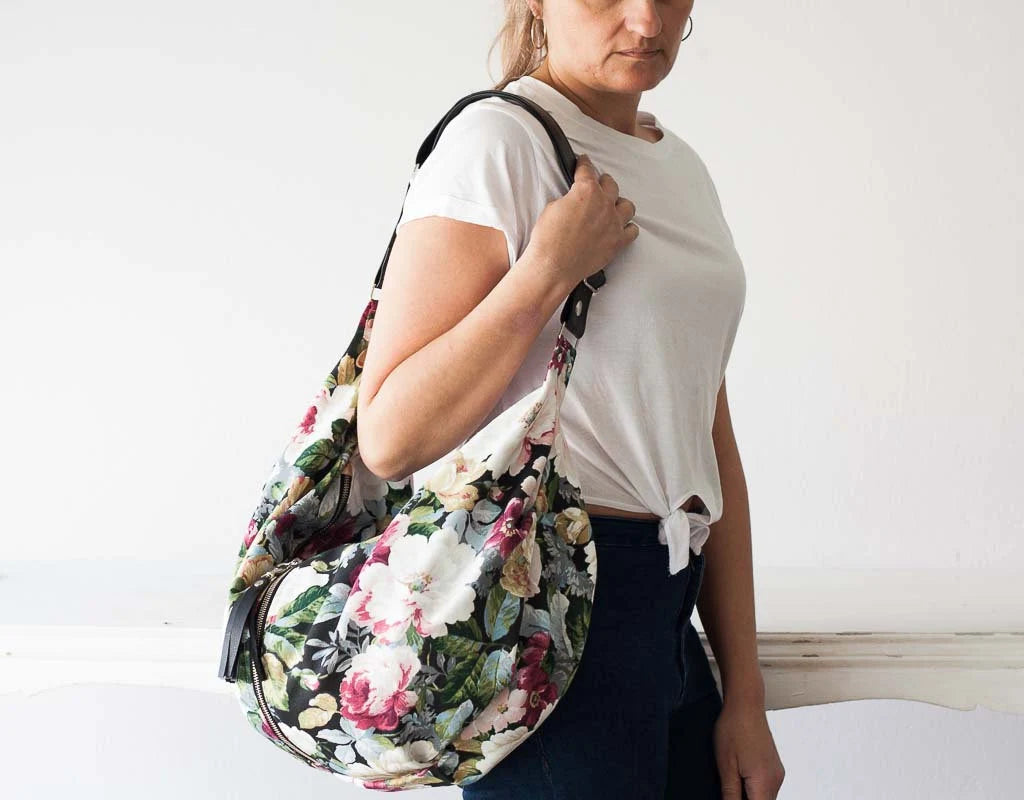 Woman carrying a floral-patterned bag against a plain background