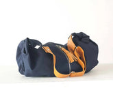 Navy blue bag with brown leather handle on a white background