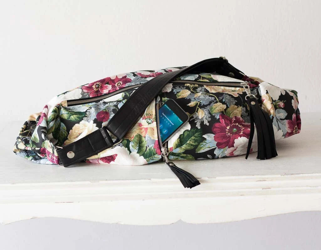 Floral patterned waist bag with a phone inside on a white surface