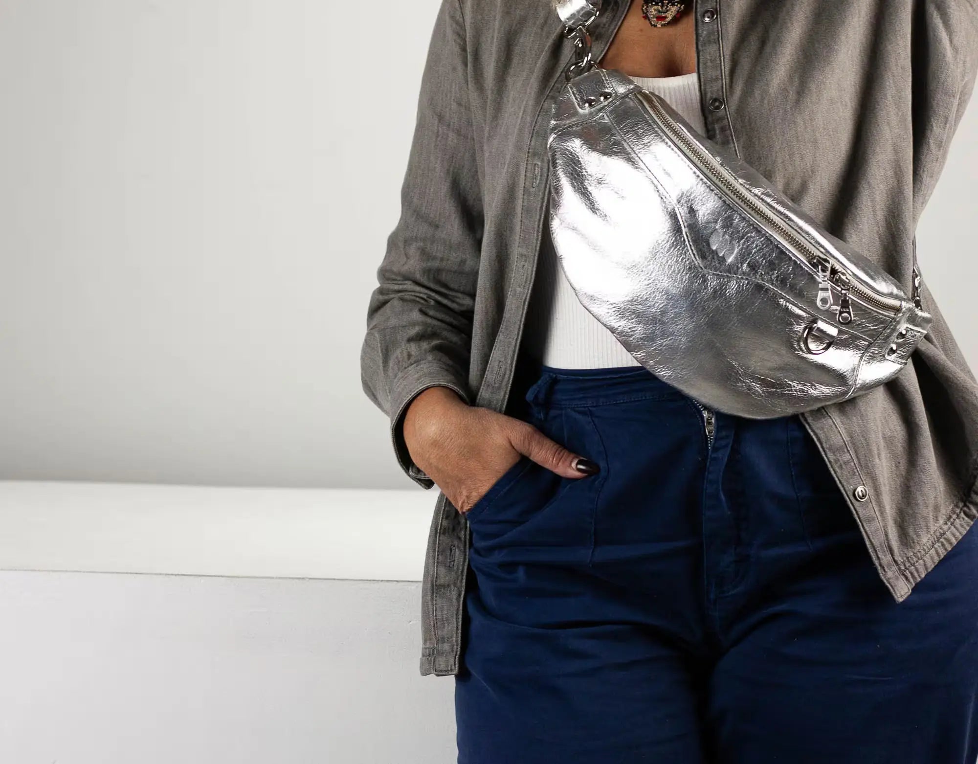 Person wearing a silver fanny pack with a neutral background