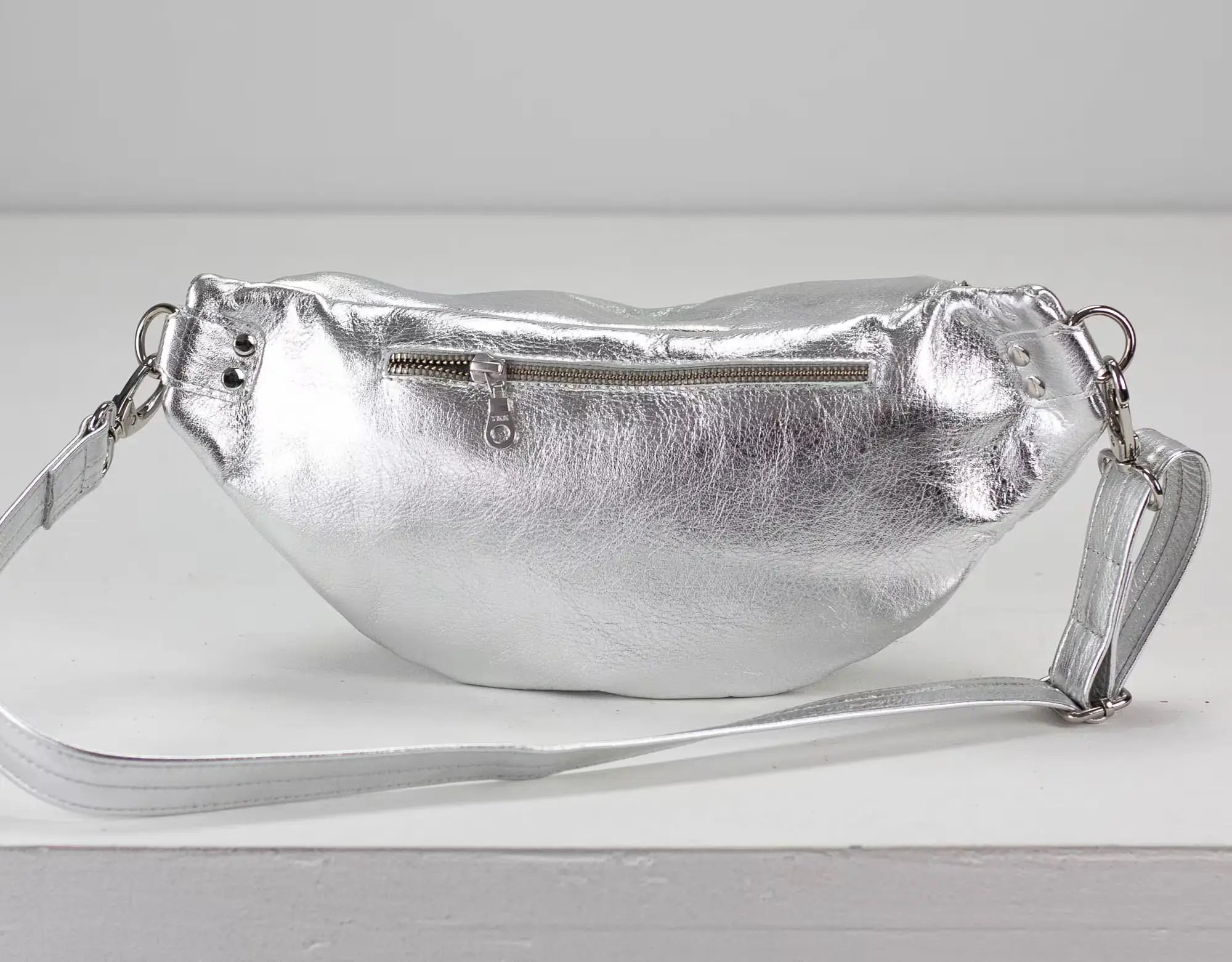 Silver metallic fanny pack on a light gray background