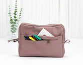Pink toiletry bag with colorful items on a white background