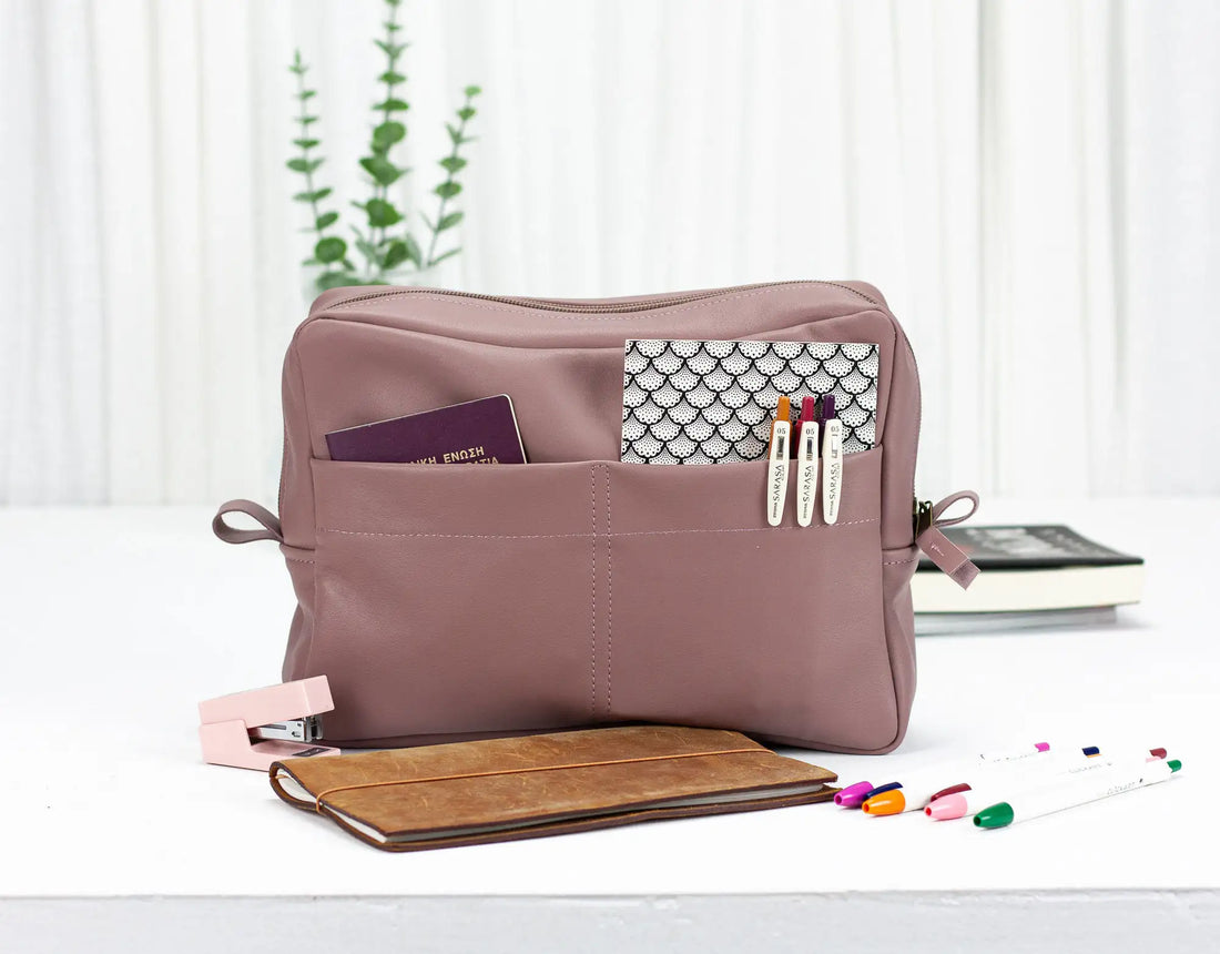Pink toiletry bag with various items on a white surface