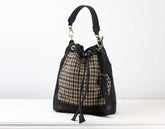 Handbag with plaid pattern and black leather accents on a white background