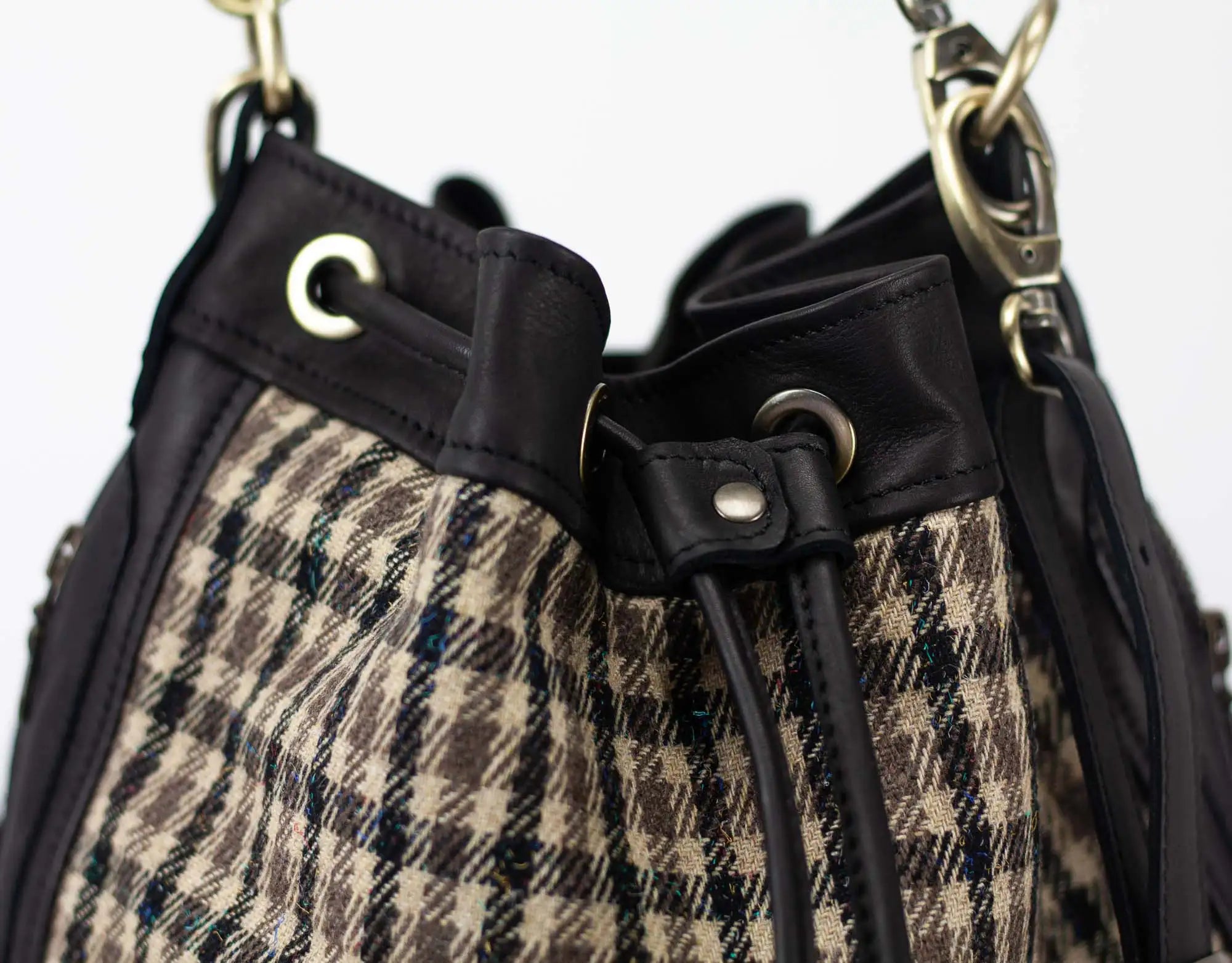 Close-up of a plaid handbag with black straps and gold hardware.