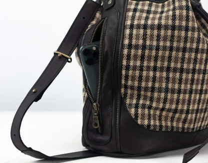 Backpack with plaid pattern and black leather accents on a white background