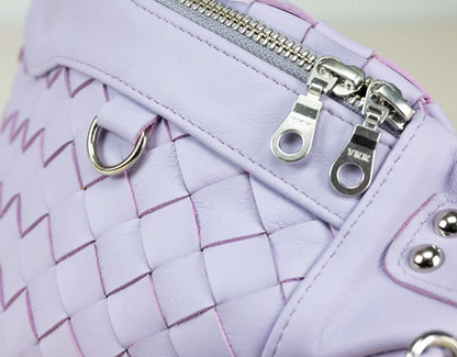Close-up of a purple woven handbag with silver zippers and hardware.