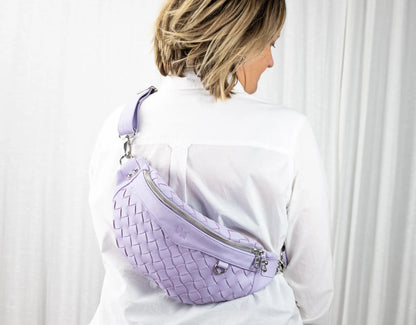 Person wearing a lavender woven waist bag against a white background