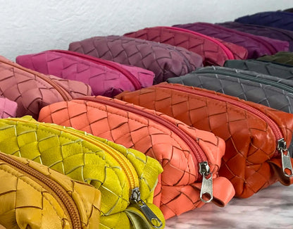 Colorful woven leather pouches arranged on a flat surface.