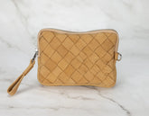 Quilted beige pouch with a strap on a marble surface