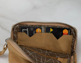 Open tan leather wallet with cards on a light gray background