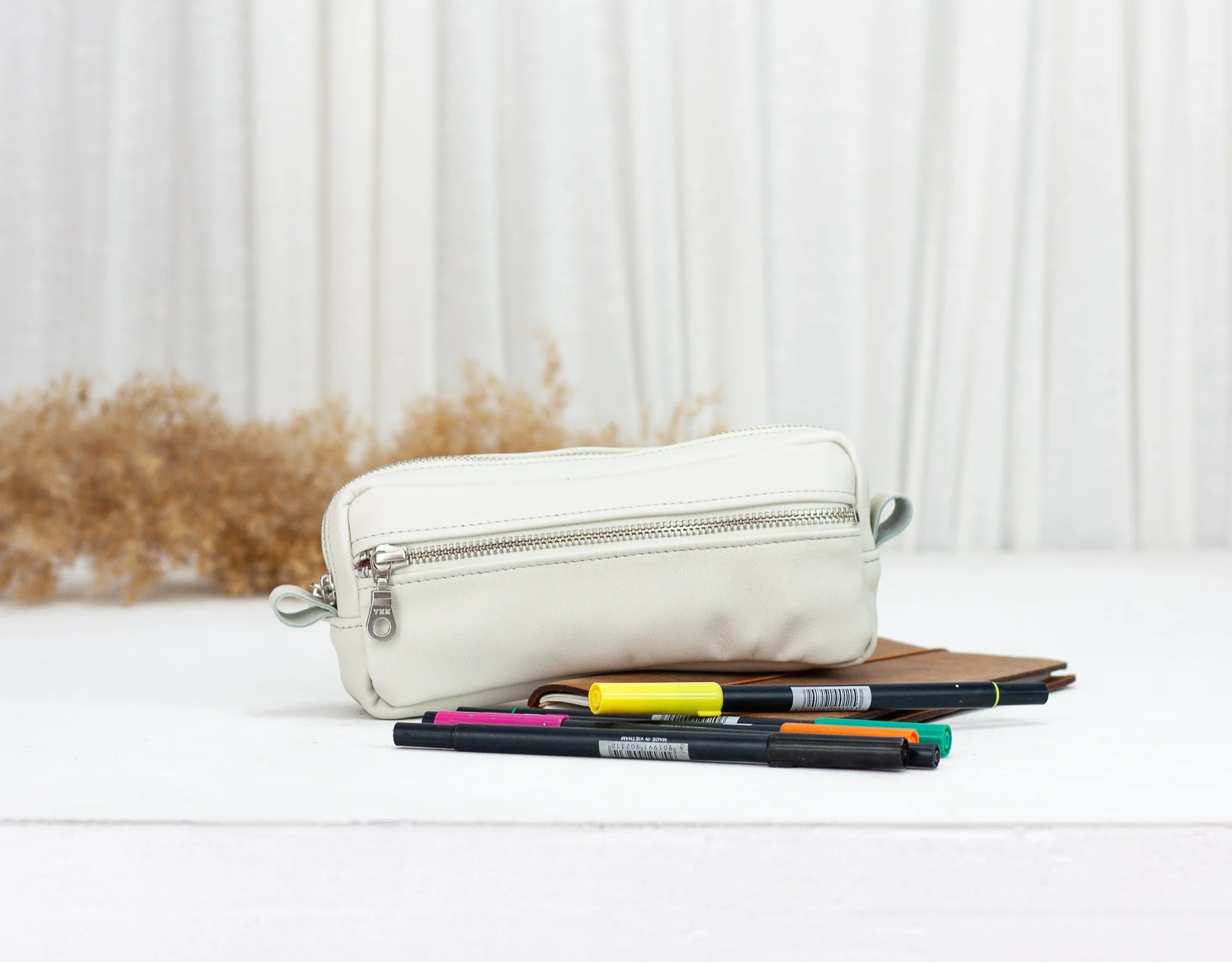 White leather pouch with pens on a light background