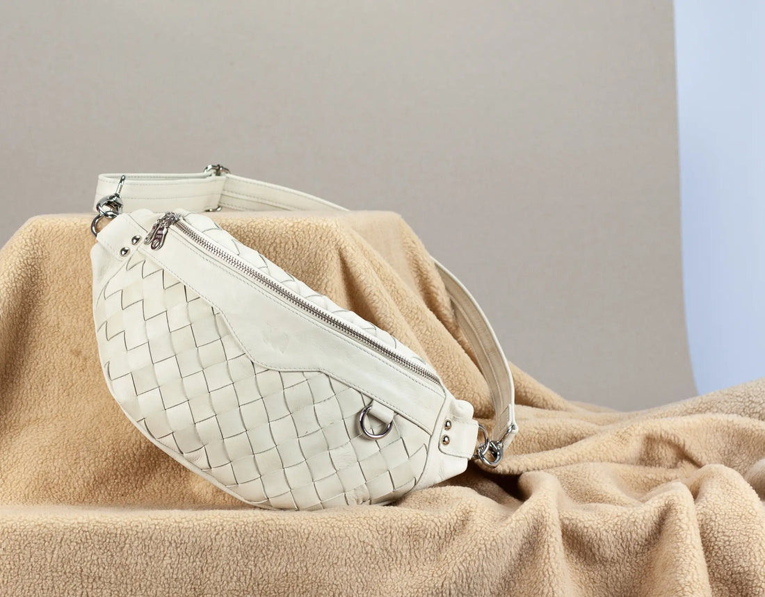 White woven handbag on a beige blanket with a neutral background