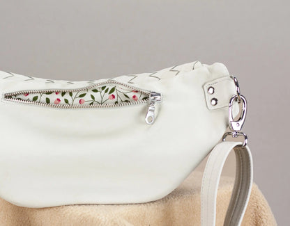 White handbag with floral zipper pull on a gray background