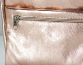 Close-up of a rose gold bag insert with a zipper on a light gray background