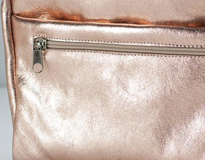 Close-up of a rose gold bag insert with a zipper on a light gray background