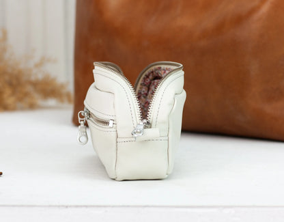 White leather pouch with floral interior on a white surface