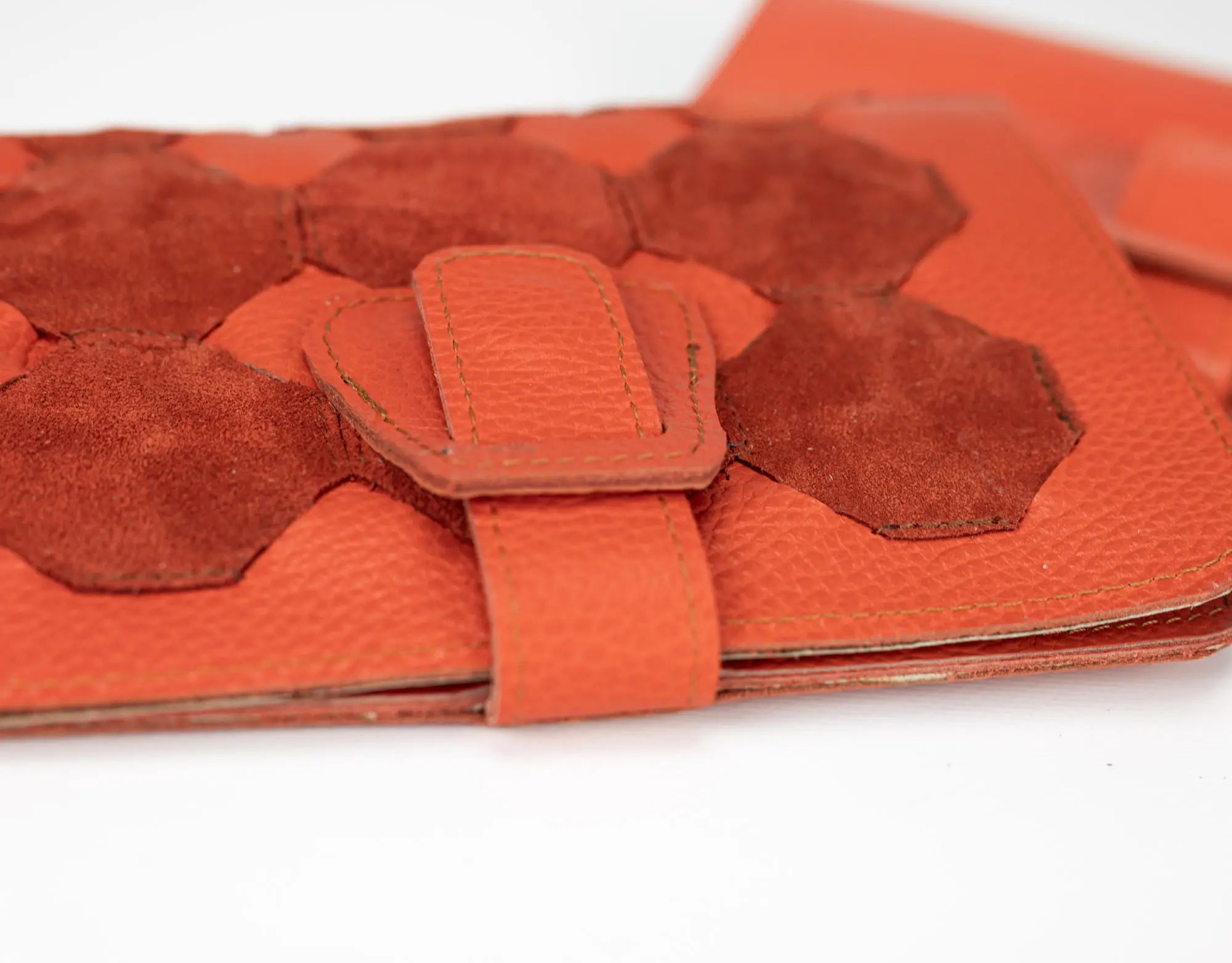 Orange leather clutch with geometric design on a white background