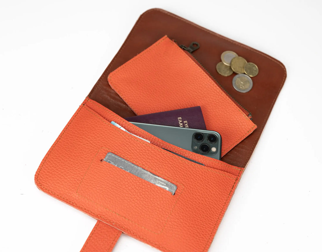 Orange leather wallet with phone, cards, and coins on a white background