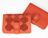 Two orange leather wallets with geometric patterns on a white background
