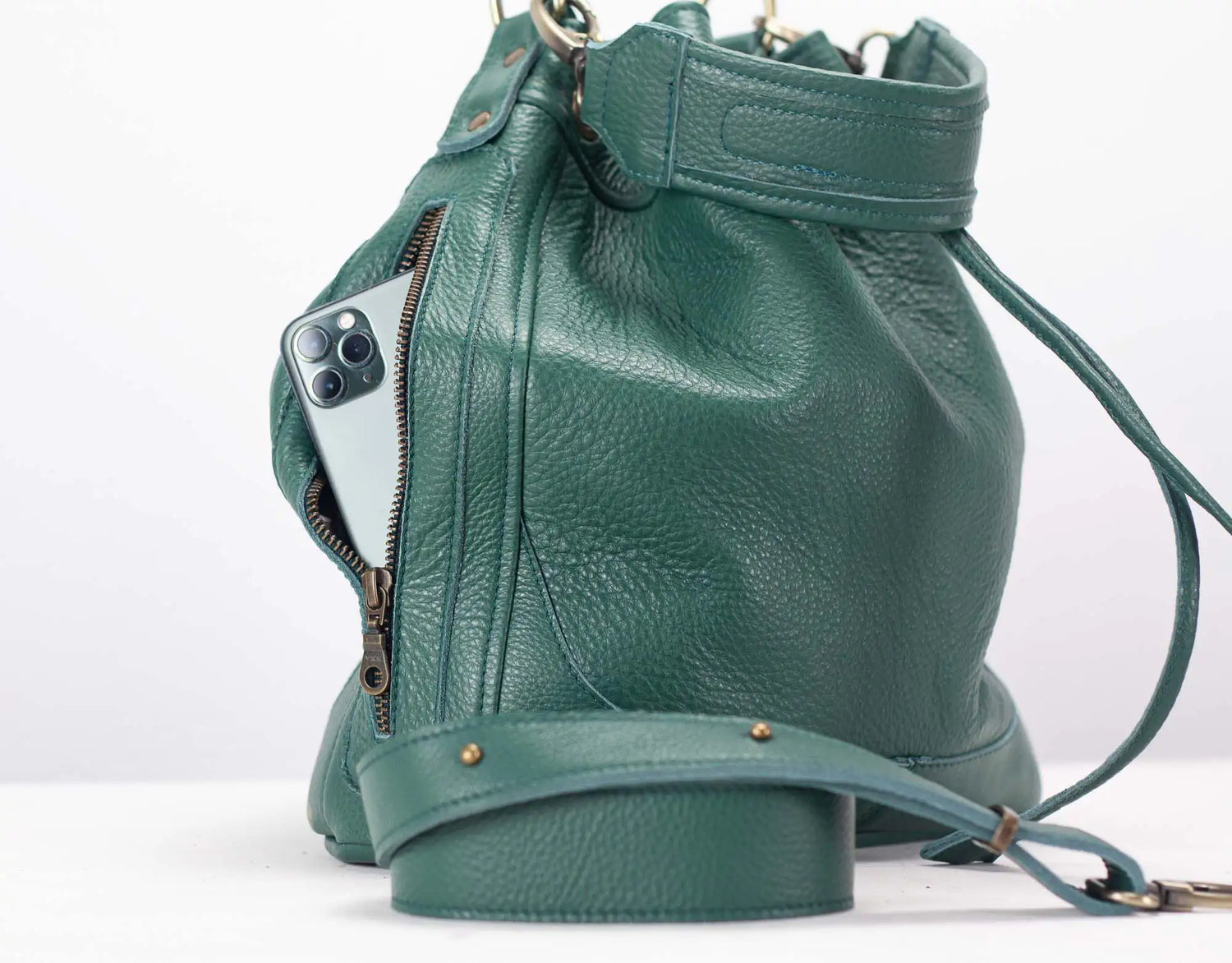Green leather bucket bag with a phone inside on a white background