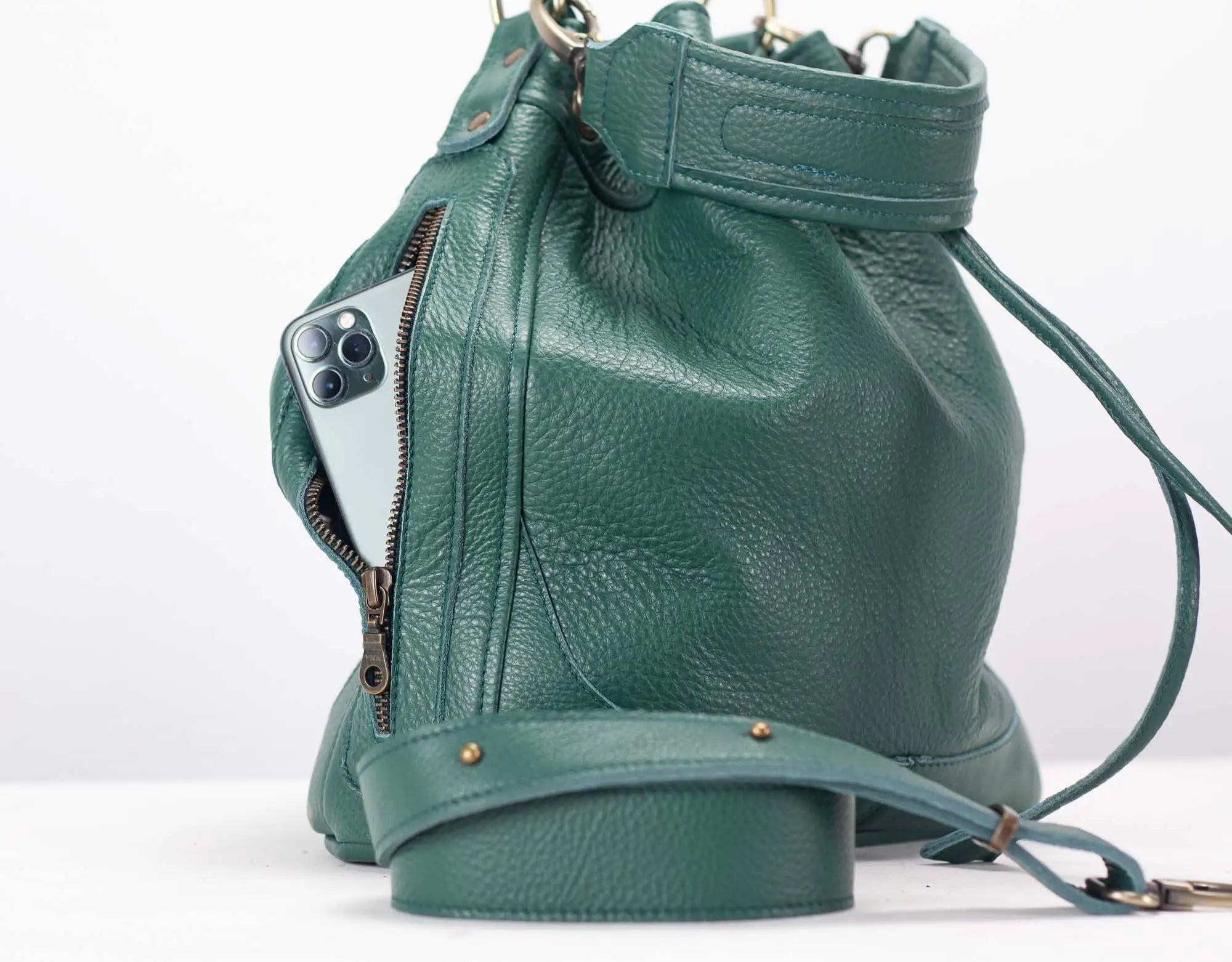 Green leather bucket bag with a phone inside on a white background