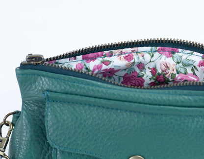 Teal handbag with floral lining on a white background