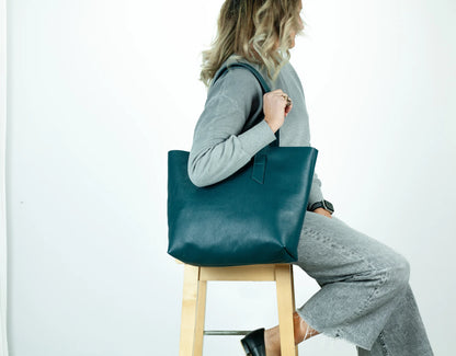 Person holding a midnight green tote bag against a white background
