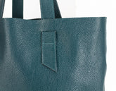 Teal leather tote bag with a pocket on a white background