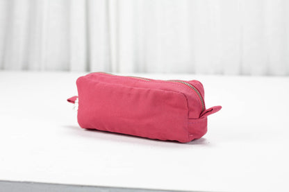 Pink cotton toiletry bag on a white surface with a light gray background