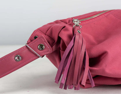Pink handbag with tassel detail on a light gray background