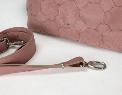 Pink leather dog leash with metal clip on a white surface, with a pink textured bag in the background.