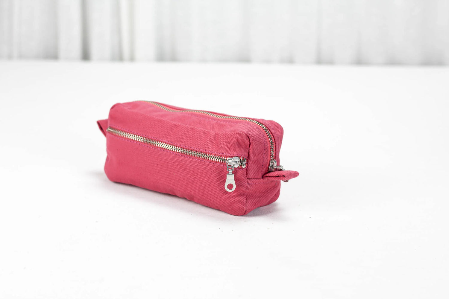 Pink toiletry bag with a silver zipper on a white surface