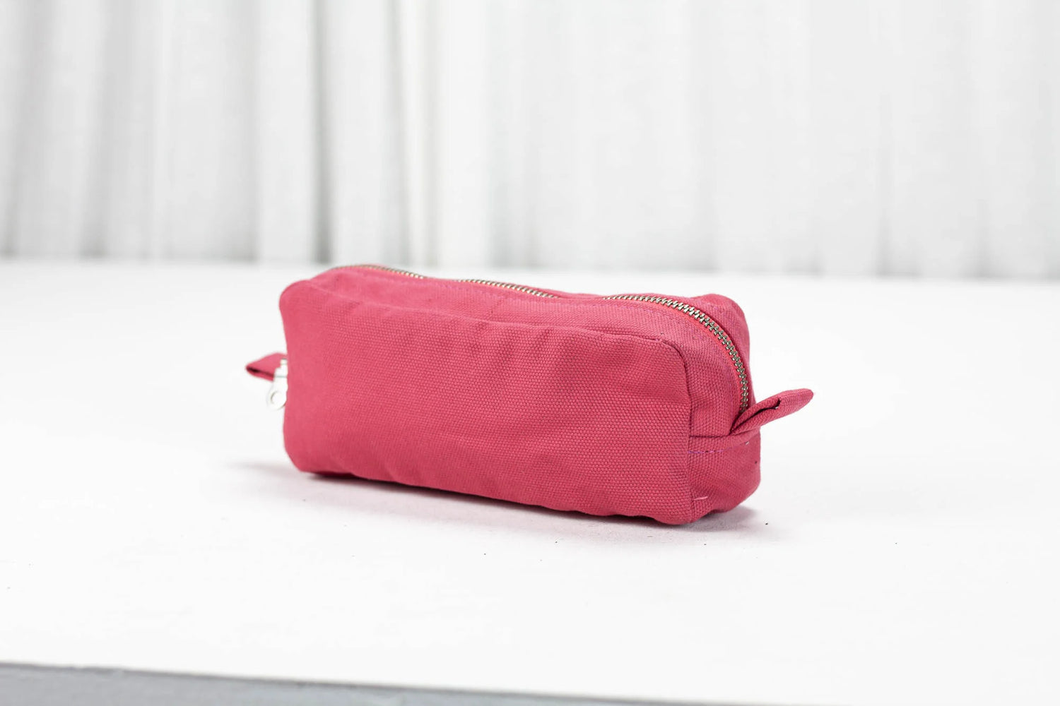 Pink toiletry bag on a white surface with a light gray background