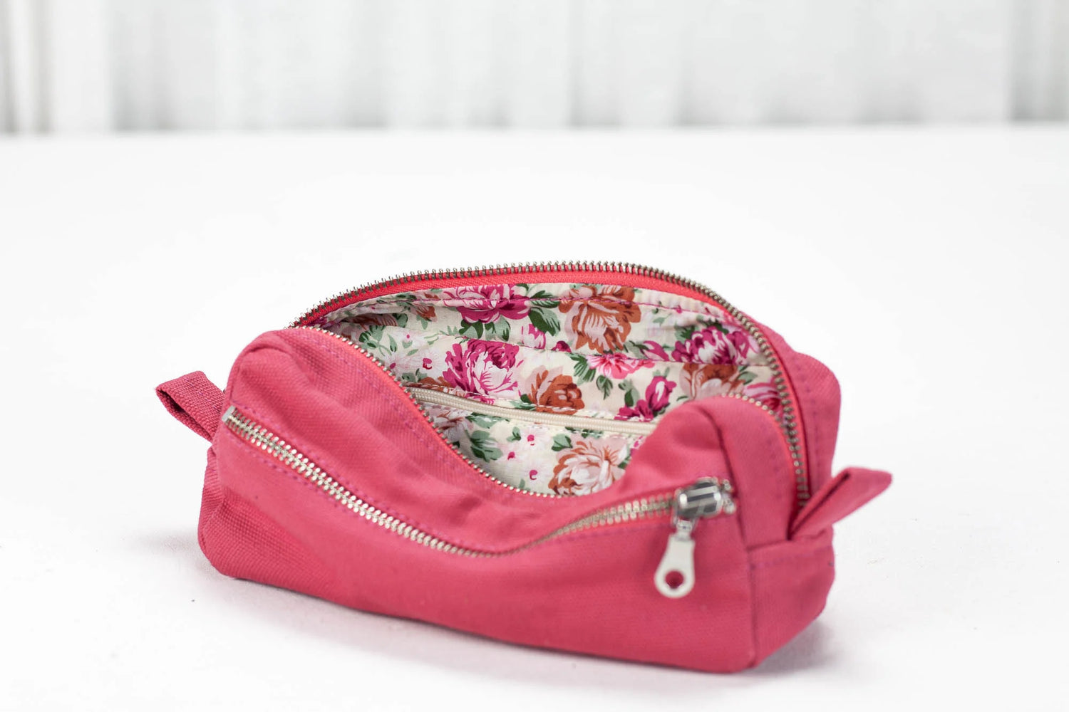 Pink cosmetic bag with floral interior on a white background